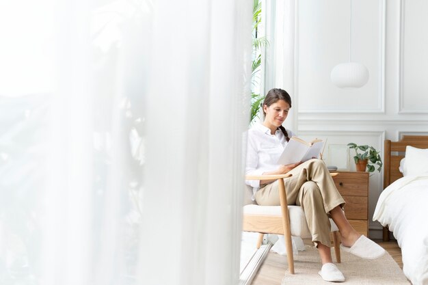 Free Photo woman reading a book in her bedroom