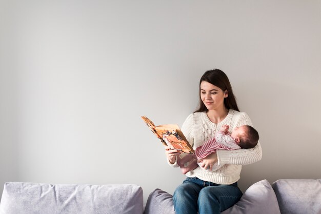 Woman reading book and holding child