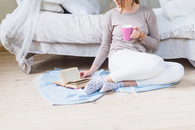 Woman reading book holding cup of coffee