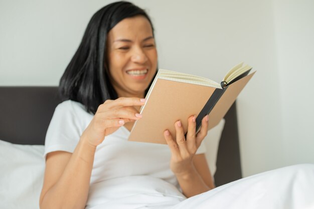 Woman reading book at home in the bedroom.