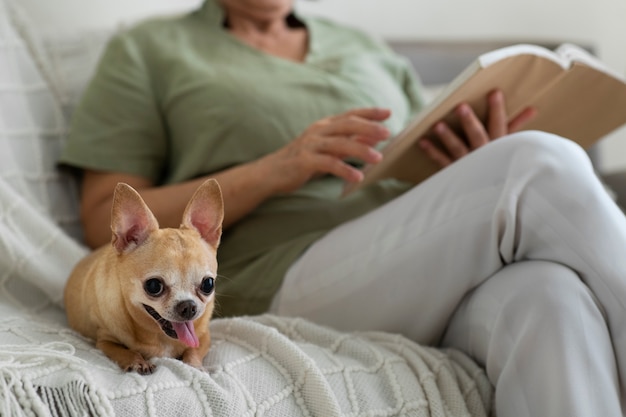 Foto gratuita donna che legge un libro a casa accanto al suo cane