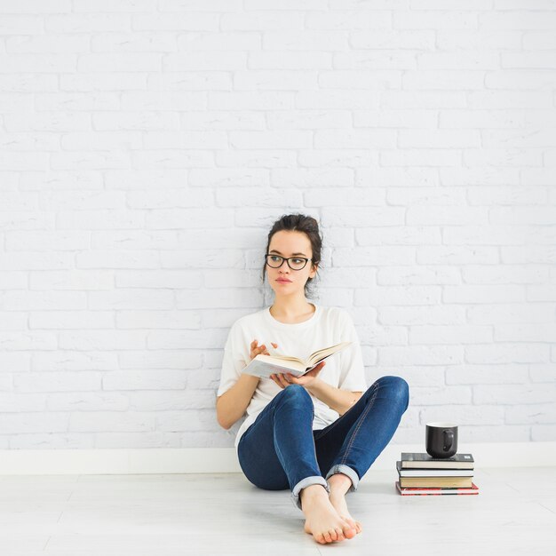 Woman reading book near cup