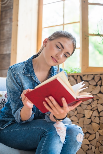 Woman reading book near window