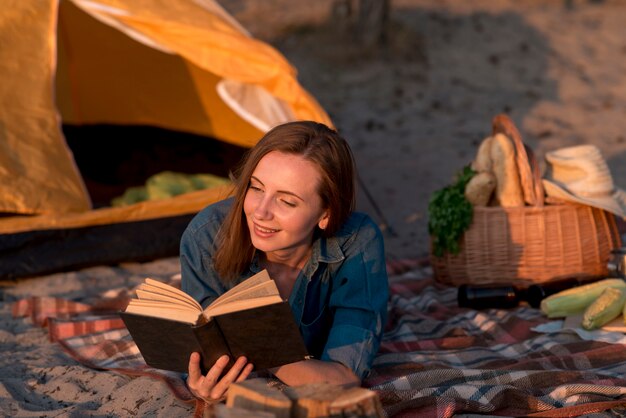 Woman reading a book on picnic blanket