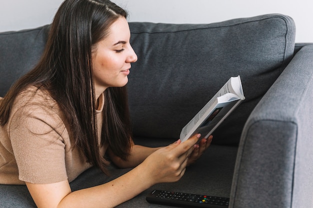 Free photo woman reading book on sofa