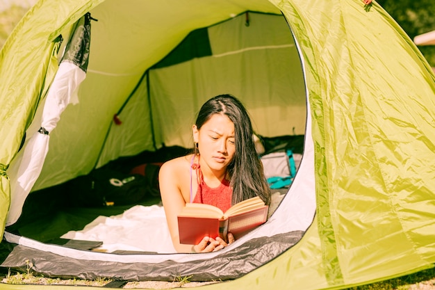 Woman reading book in tent