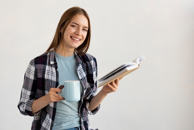 Woman reading a book while holding a cup of coffee