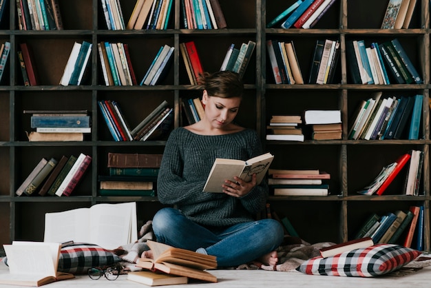 Woman reading books near old bookcase