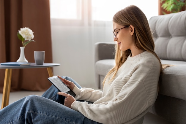 Foto gratuita donna che legge la vista laterale della rivista digitale