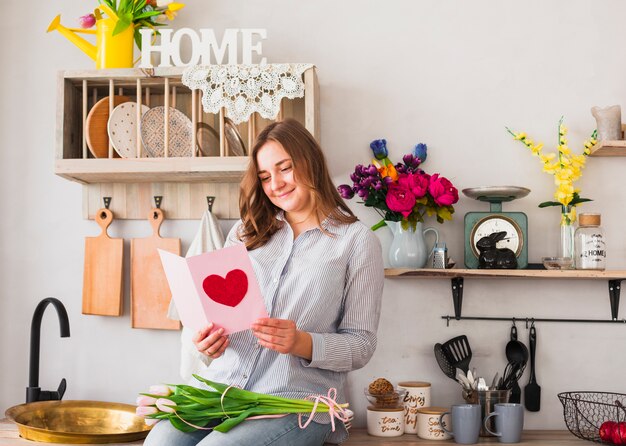 Woman reading greeting card with heart drawing 