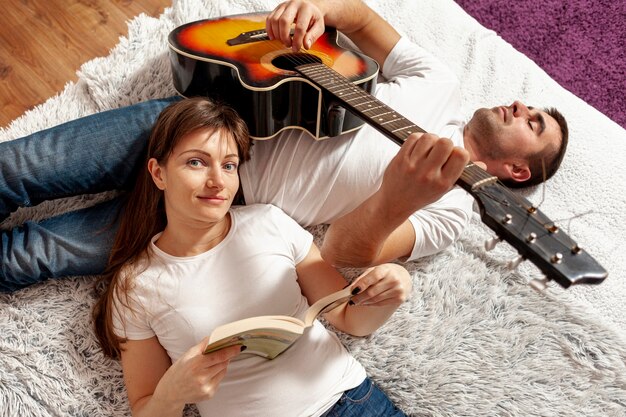 Woman reading and man playing guitar