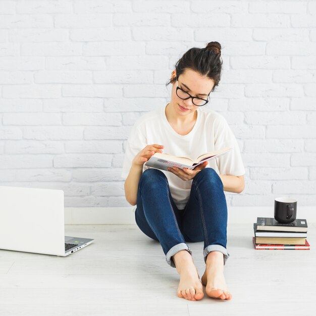 Woman reading near laptop and cup