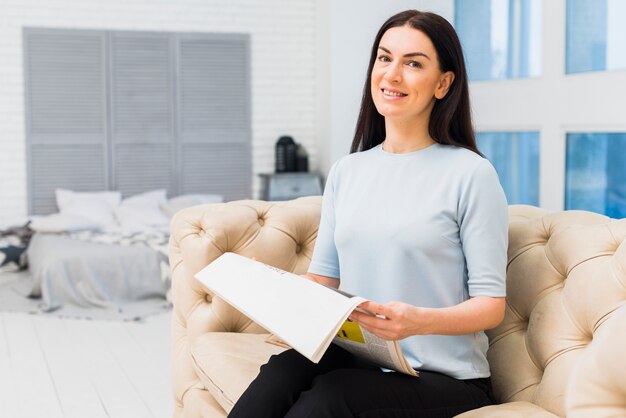 Woman reading newspaper on couch