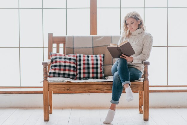 窓の近くのソファで読書をする女性