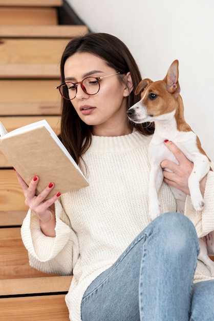 Woman reading on stairs while holding her dog