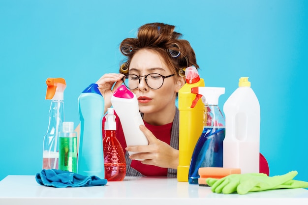 Woman reads details on bottle while doing housework, she looks tired