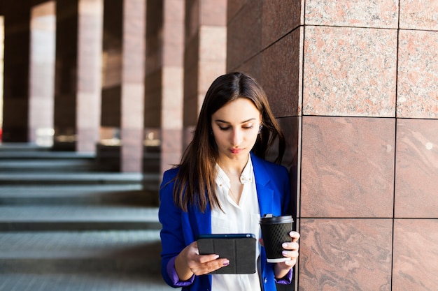 Woman reads something on the street with cup of coffee