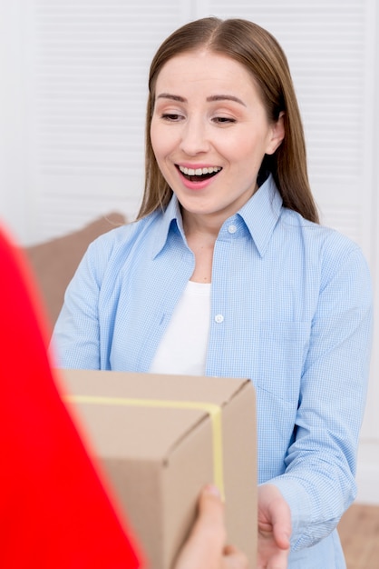 Woman receiving a cardboard box and being happy