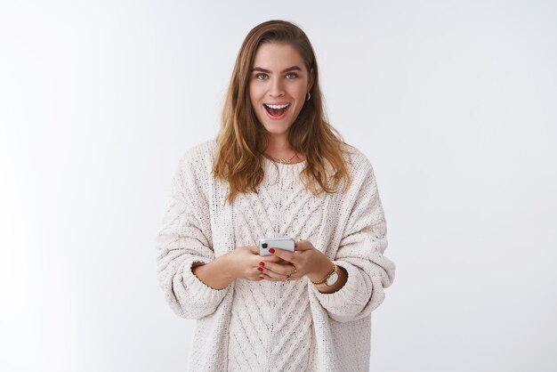 woman receiving curious message smiling mysterious holding smartphone pleased, messaging communicating online