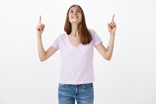 Woman receiving delight and happiness watching firewalks sparkle in sky raising head and pointing up with broad joyful smile standing entertained and amused