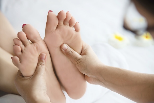 Woman receiving foot massage service from masseuse close up at hand and foot - relax in foot massage therapy service concept