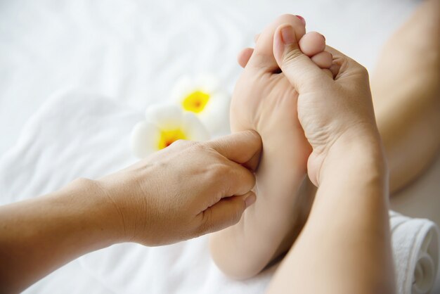 Woman receiving foot massage service from masseuse close up at hand and foot - relax in foot massage therapy service concept