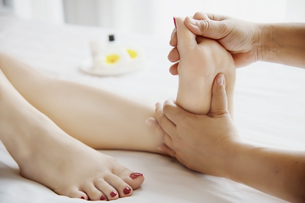 Woman receiving foot massage service from masseuse close up at hand and foot - relax in foot massage therapy service concept