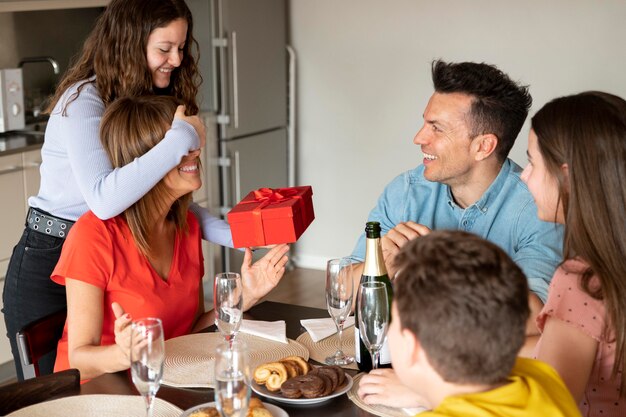 Woman receiving gift at dinner surrounded by family