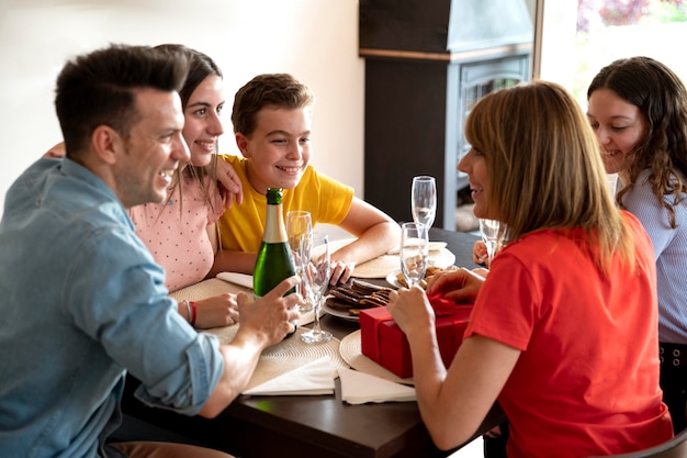 Woman receiving gift at dinner surrounded by family