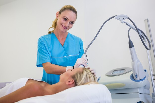 Woman receiving laser epilation treatment on her forehead