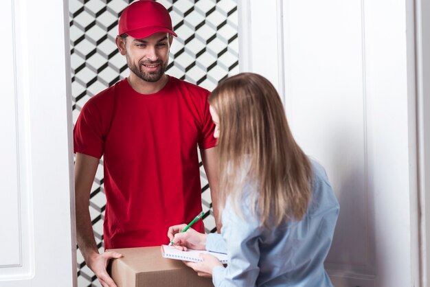 Woman receiving a package from the courier over the shoulder view