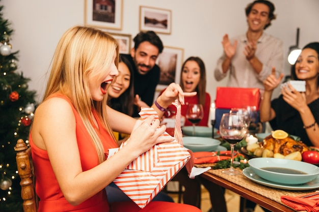 Woman receiving present from friends at christmas dinner
