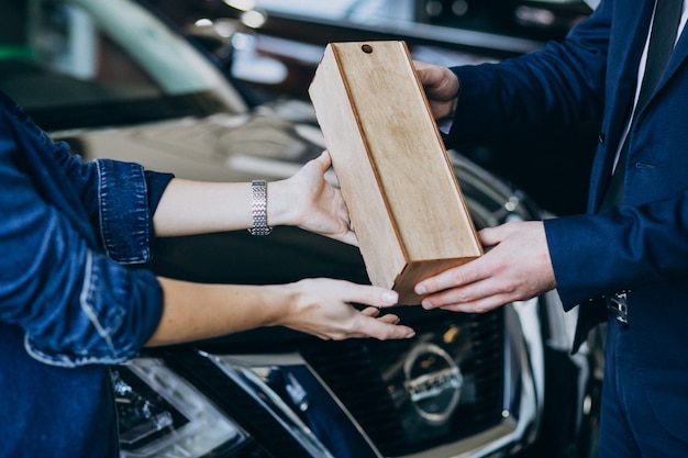 Free photo woman receiving wooden parcel in a car showroom