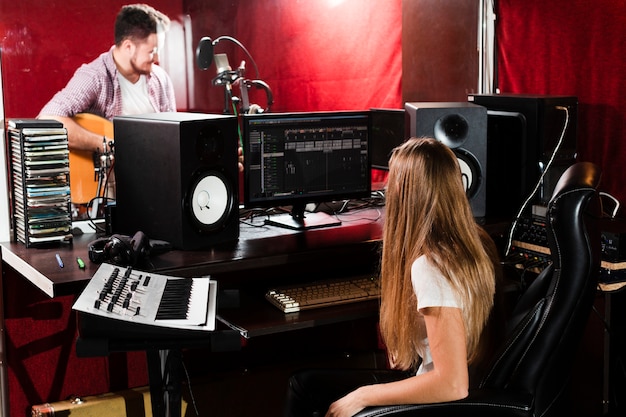 Woman records guitar and guy playing in the studio