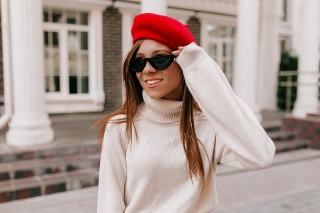 通りでポーズをとって赤いベレー帽の女性
