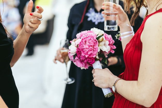 Free photo woman in red dress holds a glass while talking with people