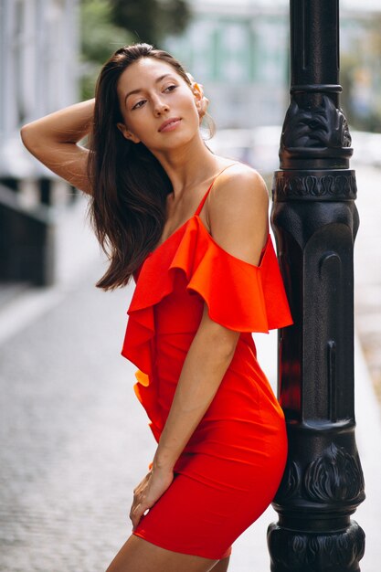 Woman in red dress model posing outside