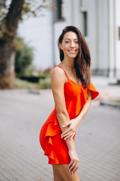 Woman in red dress model posing outside