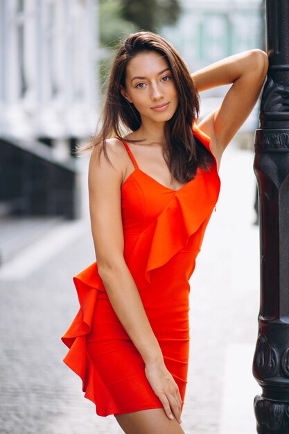 Woman in red dress model posing outside