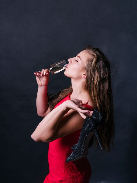 Женщина в красном пить шампанское из стекла
