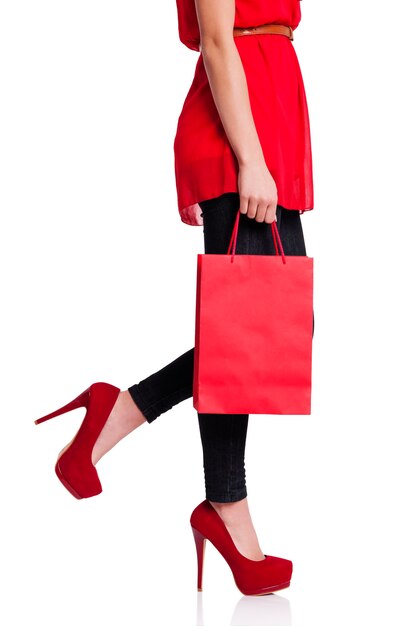 Woman in red high heels holding red shopping bag