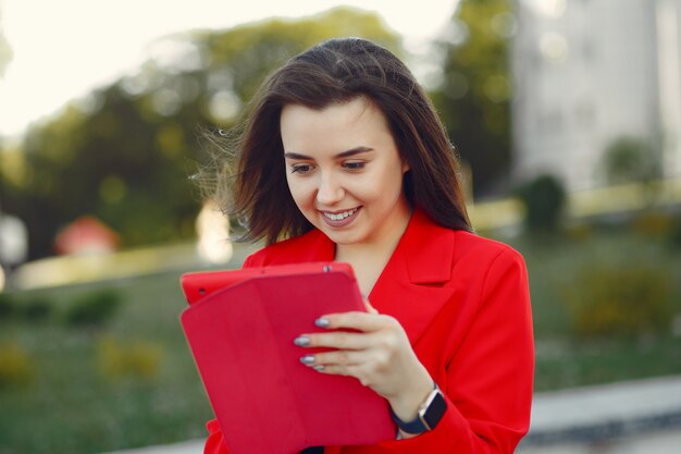 Женщина в красной куртке с помощью планшета