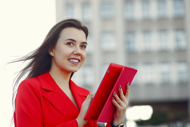 タブレットを使用して赤いジャケットの女性