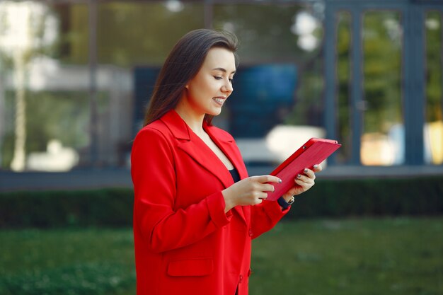 Женщина в красной куртке с помощью планшета