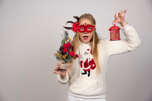 Woman in red mask showing lamp gift and pinetree surprisingly.