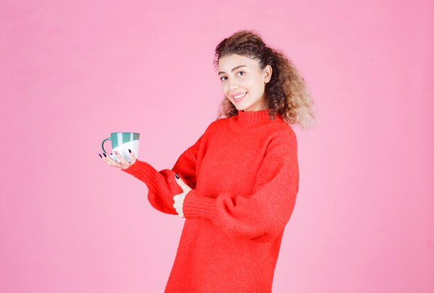 woman in red shirt holding a coffee mug and enjoying the taste.
