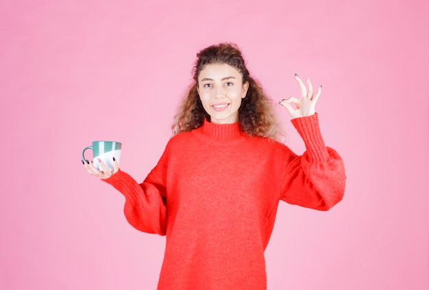 woman in red shirt holding a coffee mug and enjoying the taste.