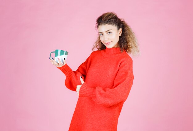 woman in red shirt holding a coffee mug and enjoying the taste.