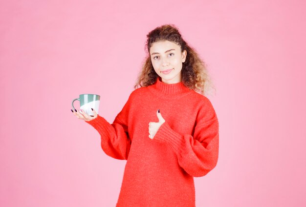 woman in red shirt holding a coffee mug and enjoying the taste.