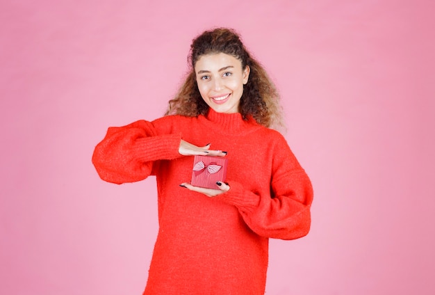 woman in red shirt holding a small red gift box.